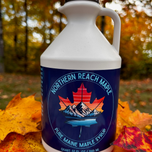 A quart jug of pure maine maple syrup among the autumn leaves of Northern Maine.