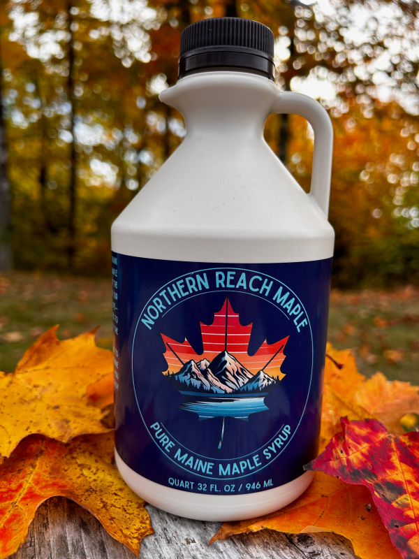 A quart jug of pure maine maple syrup among the autumn leaves of Northern Maine.