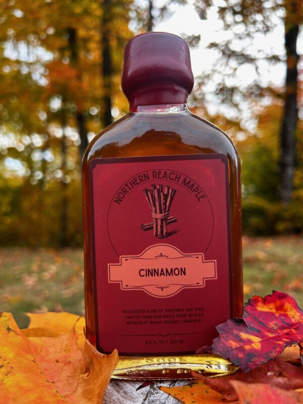 A bottle of cinnamon infused maple syrup among the autumn leaves
