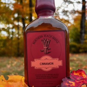 A bottle of cinnamon infused maple syrup among the autumn leaves