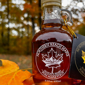 A bottle of Season's Finest, capturing the best of our maple syrup season in front of autumn leaves in Northern Maine.