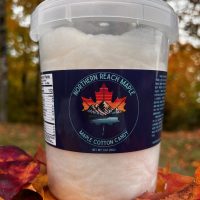 A bucket of Maine Maple Cotton Candy shown among autumn leaves in Northern Maine.