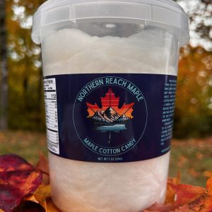 A bucket of Maine Maple Cotton Candy shown among autumn leaves in Northern Maine.