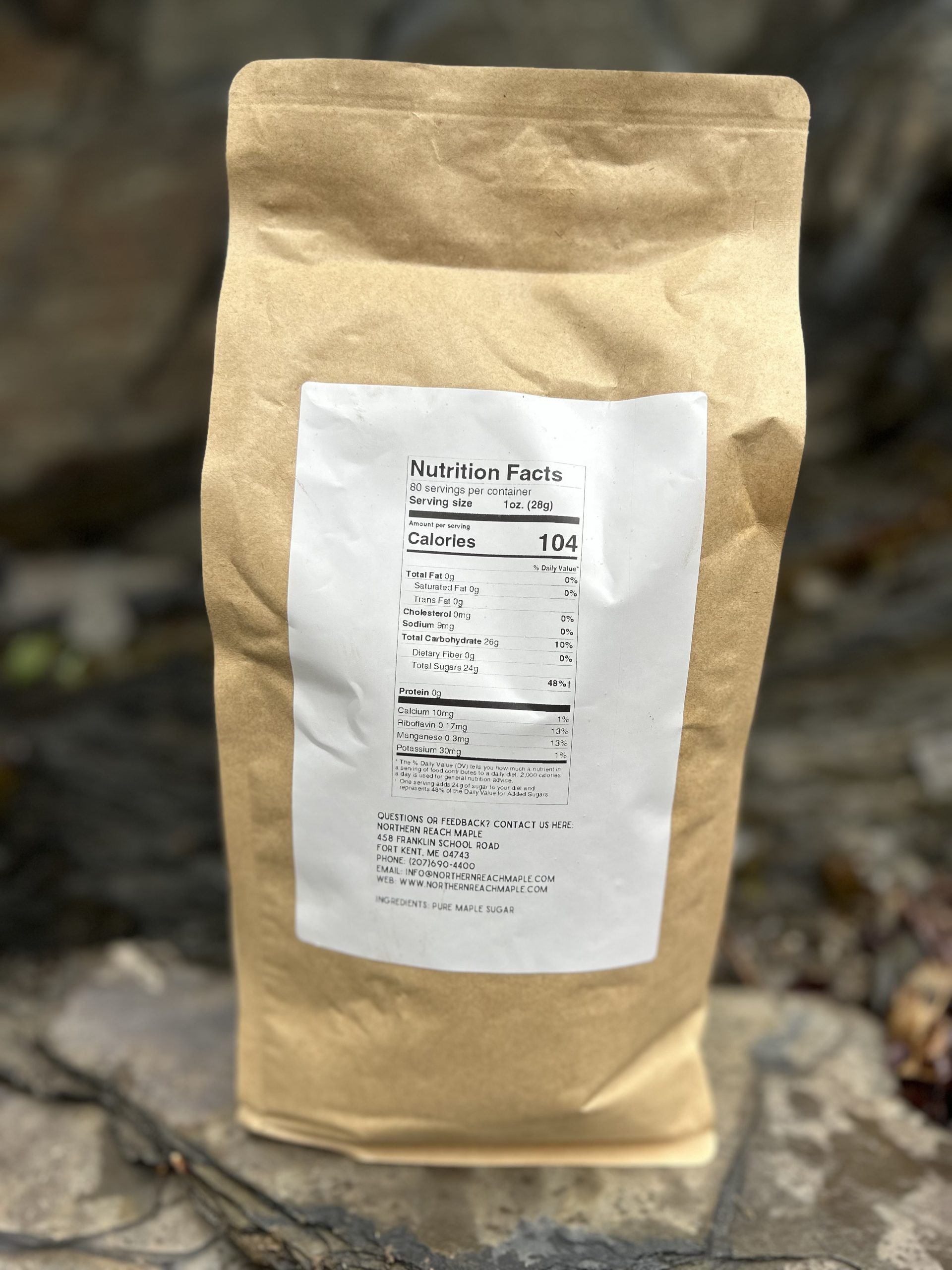 The back side of a five pound bag of Northern Reach Maple pure maple sugar pictured in front of a slate rock ledge
