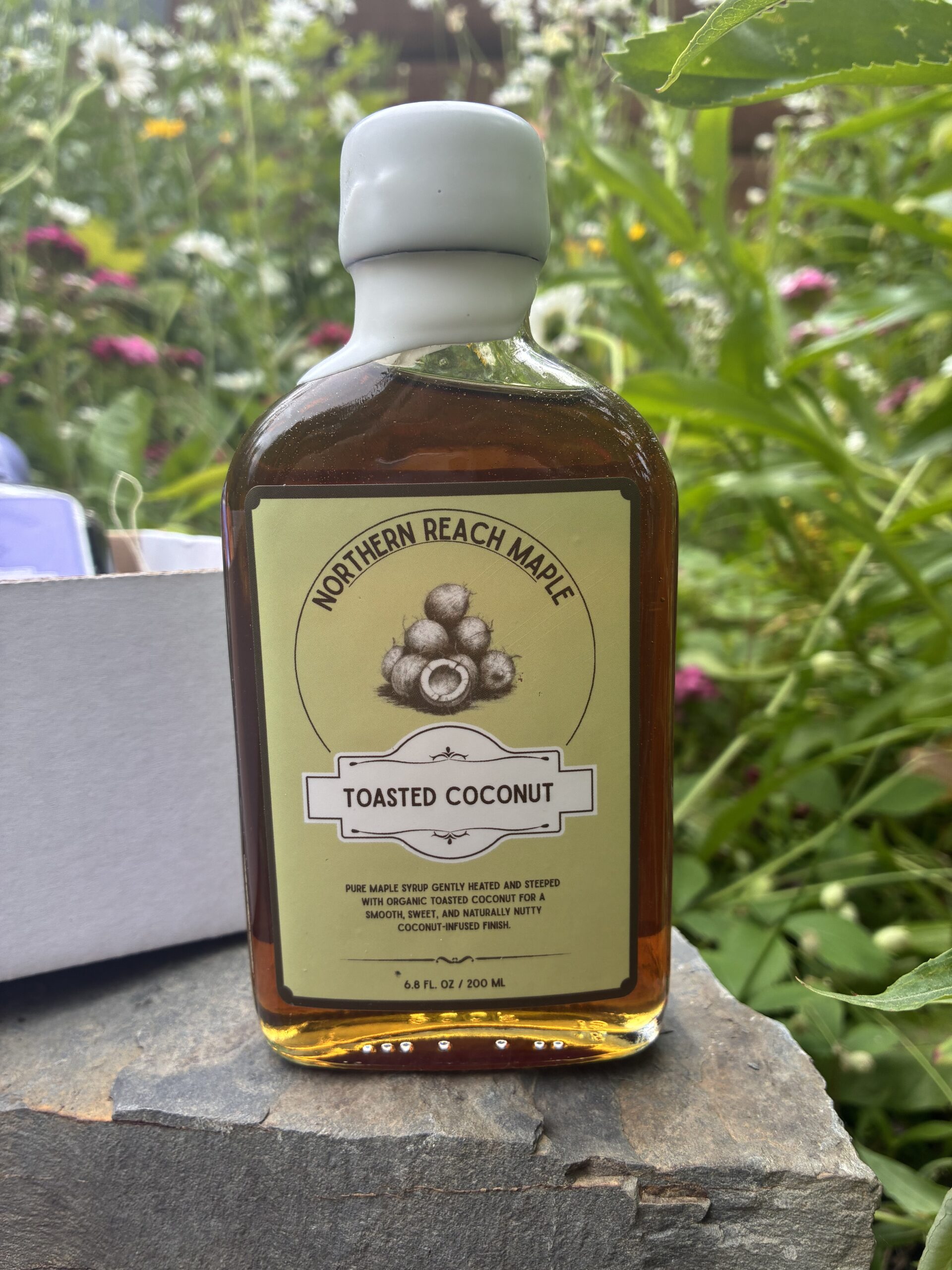 Toasted Coconut maple syrup in front of the Berry, Cacao, and Copra Flavor Trio box.