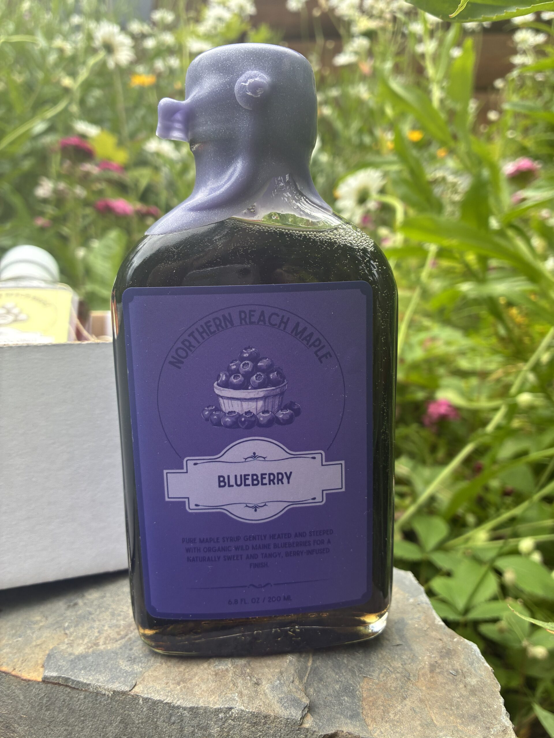 Maine Blueberry maple syrup in front of the Berry, Cacao, and Copra Flavor Trio box.