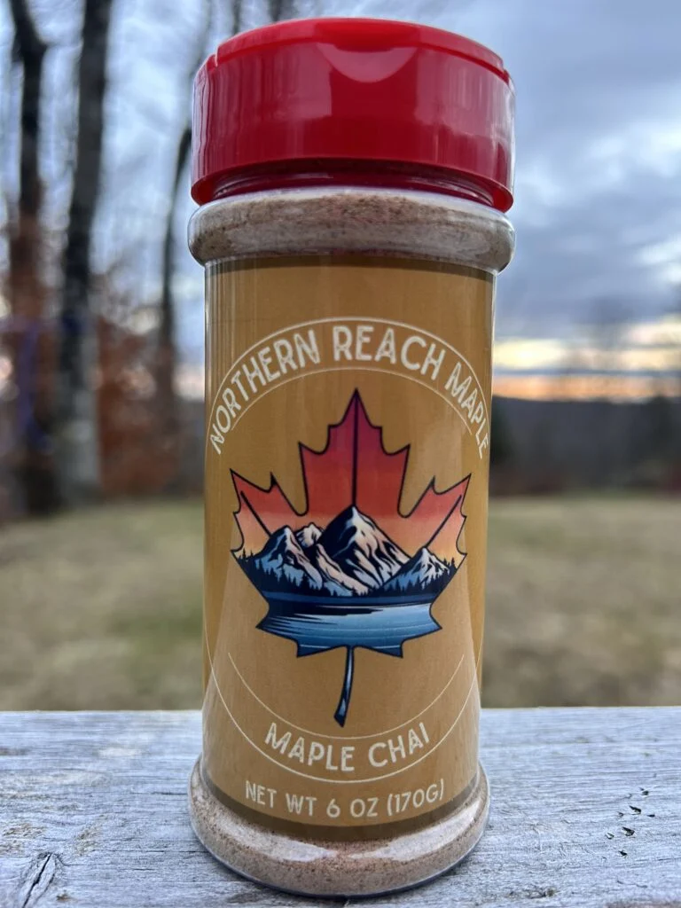 Maple Chai 6oz shaker with real Maine Maple Sugar. Pictured on a picnic table showing a sunset in the background.