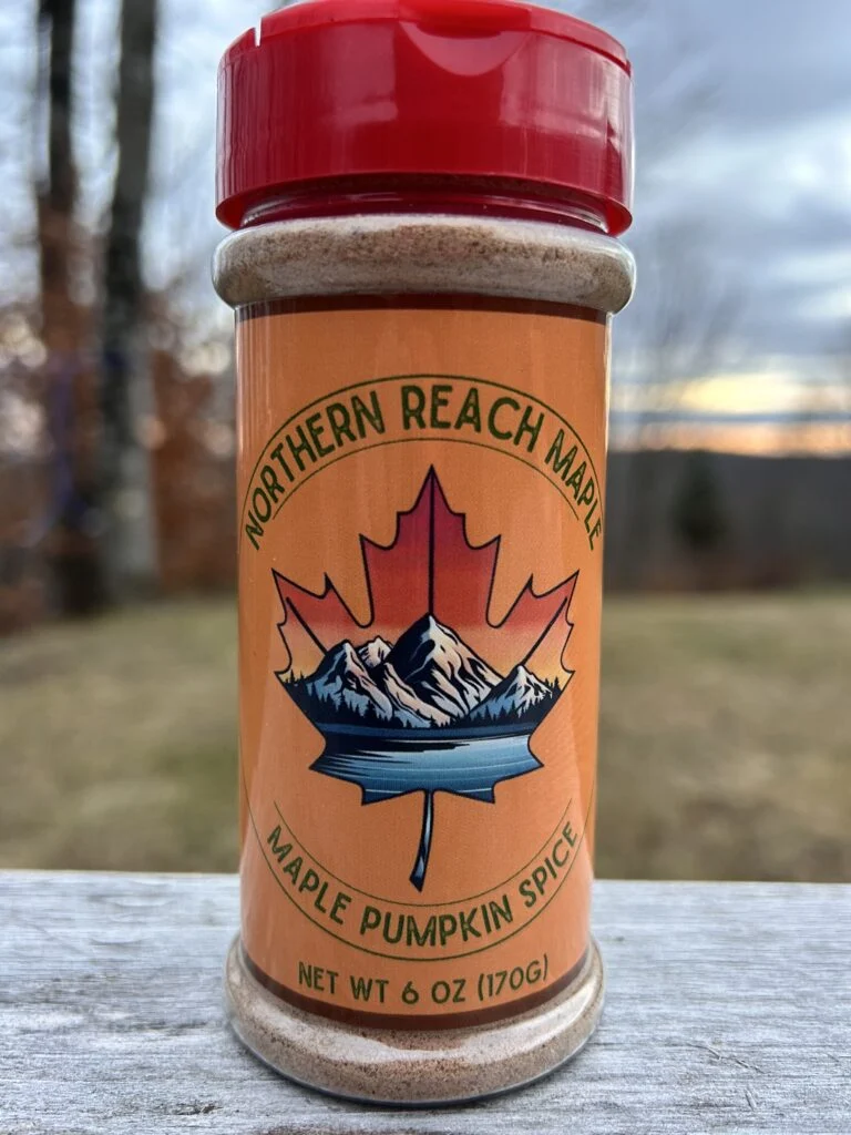 A 6oz Maple Pumpkin Spice shaker on top of a picnic table with sunset in the background.
